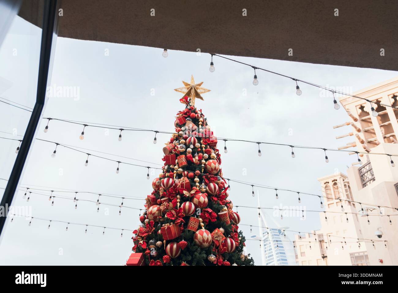 Geschmückter Weihnachtsbaum in Dubai mit festlicher Marktatmosphäre und Burj Al Arab Hintergrund Stockfoto