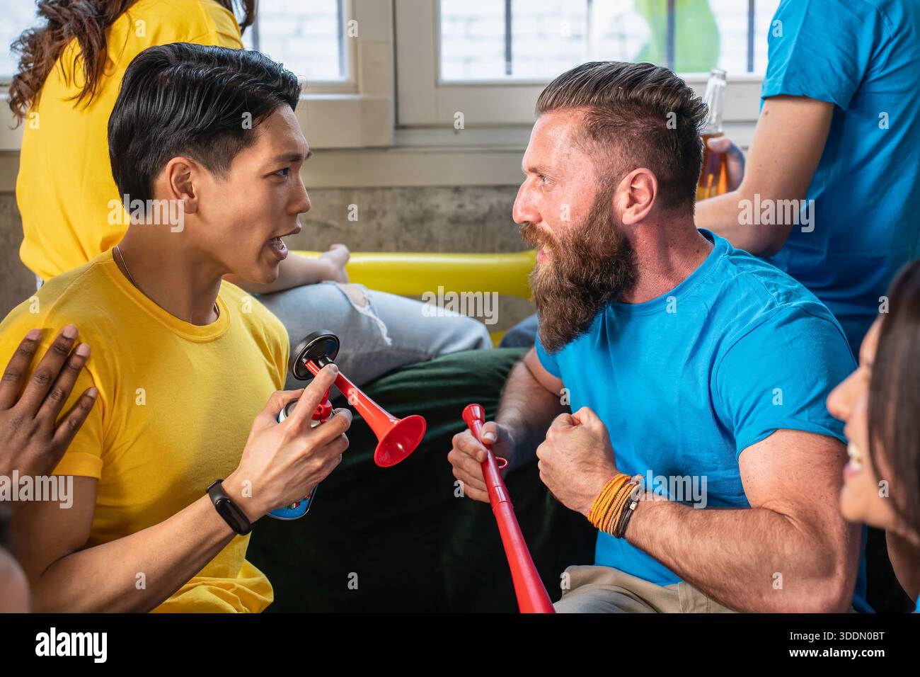 Zwei leidenschaftliche Sportfans aus gegnerischen Teams streiten sich während einer lebhaften Spielparty spielerisch und zeigen intensive Emotionen und Teamgeist. Soziale Ga Stockfoto
