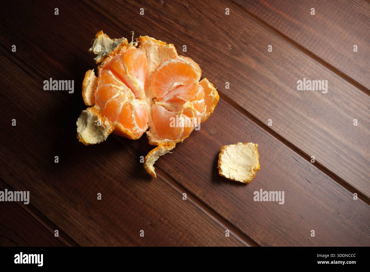 Eine lebendige Mandarine steht offen auf einer rustikalen Holzoberfläche, die zum Genießen bereit ist. Stockfoto