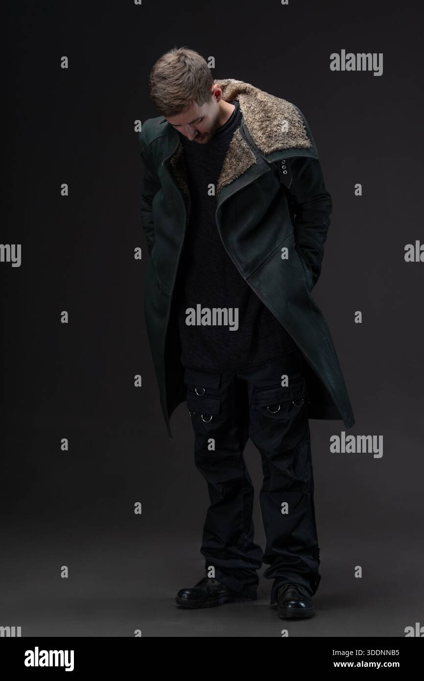 Junger Mann in hochgestecktem Mantel, der die Hälfte seines Gesichts bedeckt, melancholischer Cyberpunk-Stil. Stockfoto