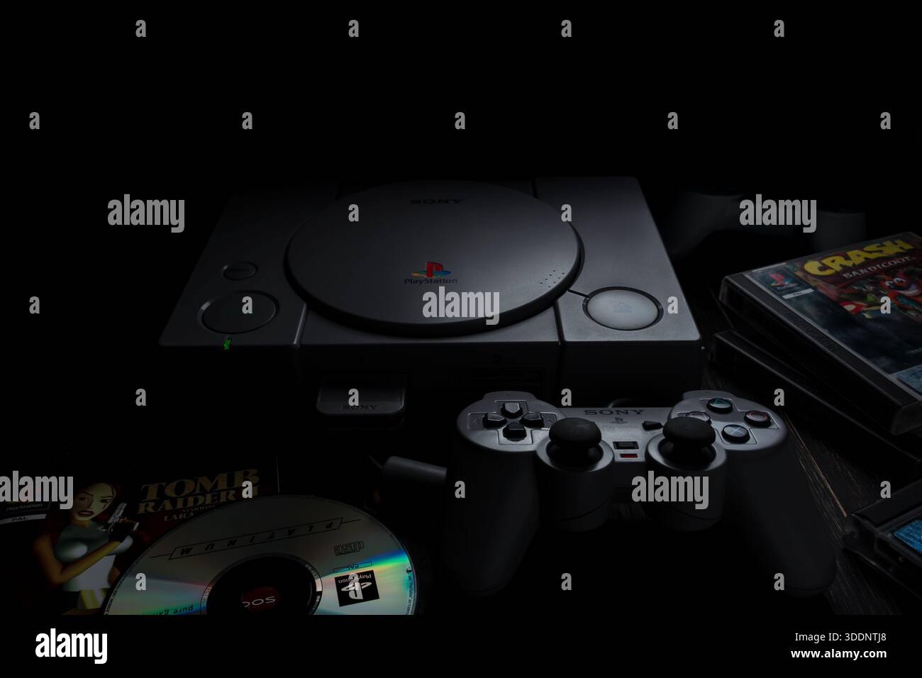 1. Januar 2026, Odessa, Ukraine. Retro-PlayStation 1-Konsole von Sony mit Controller und Spielen auf dunklem Hintergrund. Stockfoto