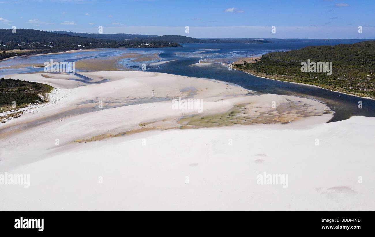 Erleben Sie die ruhige Schönheit der Sanddünen, die auf einen ruhigen Fluss treffen und die Weite der Natur und die friedliche Landschaft zeigen. Stockfoto