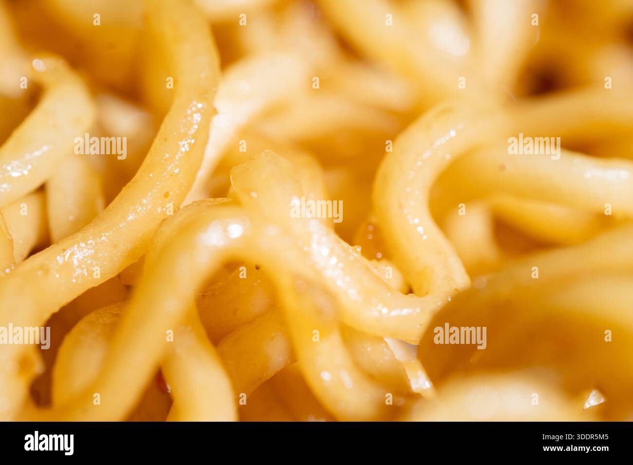 Extreme Nahaufnahme von gekochten gelben Lockennudeln. Köstliche Ramen Textur Hintergrund für Lebensmittelindustrie, Menügestaltung und asiatische Küche. Stockfoto