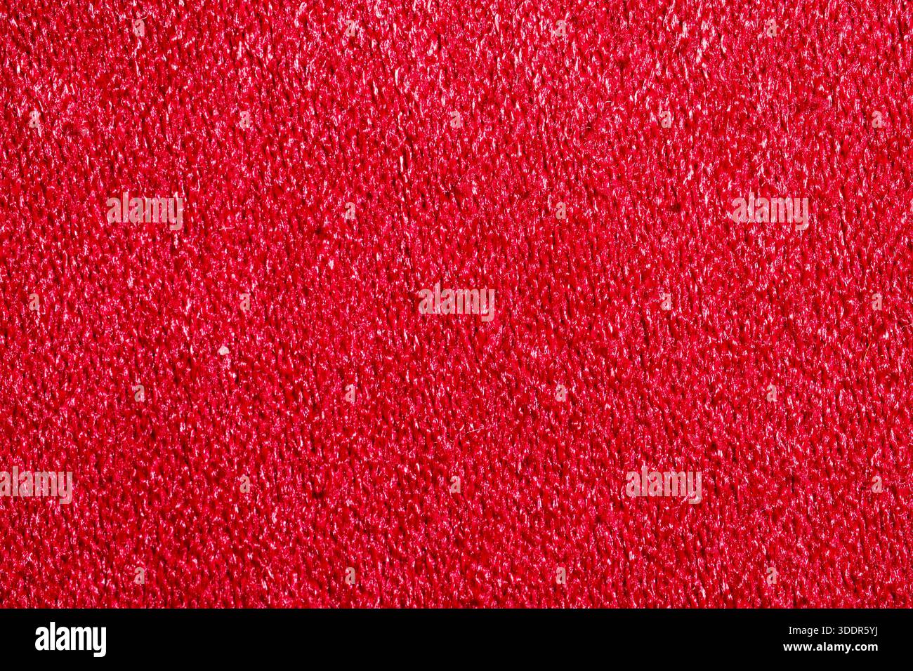 Extrem Nahaufnahme aus leuchtend rotem Material. Detaillierte weiche Textiloberfläche und Fasermuster für Mode, Polsterung und luxuriöses Design. Stockfoto