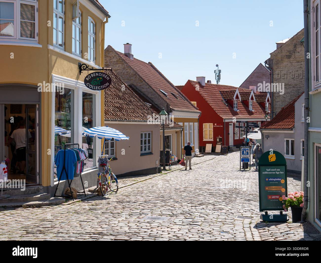 Historische Kopfsteinpflasterstraße Adelgade mit Geschäften und Fußgängern in der Altstadt von Ebeltoft, Jütland, Dänemark Stockfoto