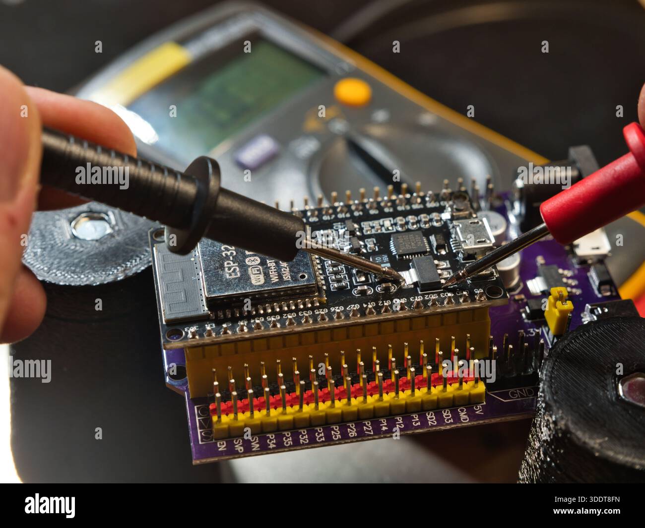 Mikrocontroller-Platine für den technischen Test; Nahaufnahme eines Ingenieurs, der die Spannung auf einer modernen Mikrocontroller-Entwicklungsplatine (PCB) mit einem digitalen m testet Stockfoto