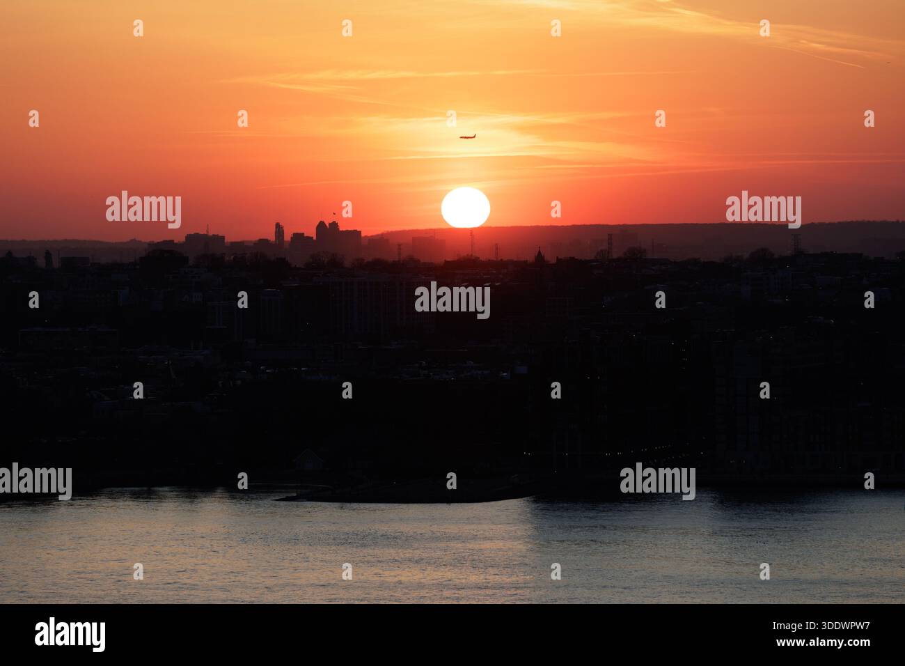 Ein Jet-Flugzeug fliegt über der Sonne über der Skyline von NJ. Stockfoto