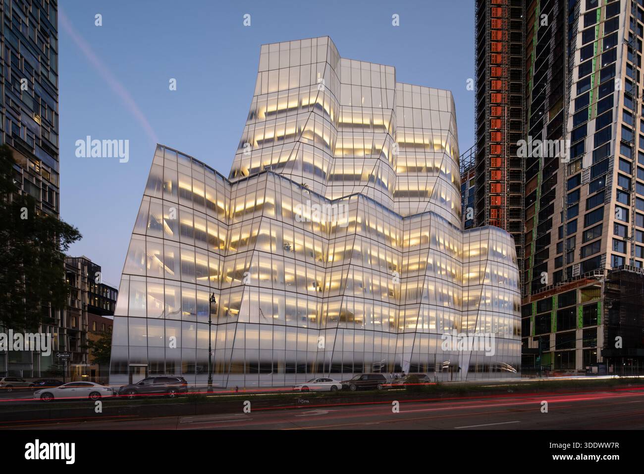 Das IAC-Gebäude in Chelsea, NYC, beleuchtet bei Nacht. Die von Frank Gehry entworfene Glasfassade leuchtet und hebt die einzigartigen segelähnlichen Kurven hervor. Stockfoto