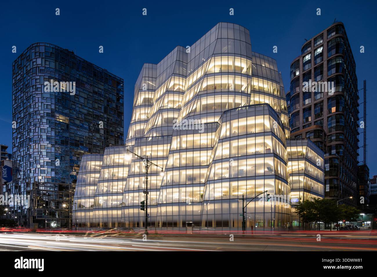 Das IAC-Gebäude in Chelsea, NYC, beleuchtet bei Nacht. Die von Frank Gehry entworfene Glasfassade leuchtet und hebt die einzigartigen segelähnlichen Kurven hervor. Stockfoto