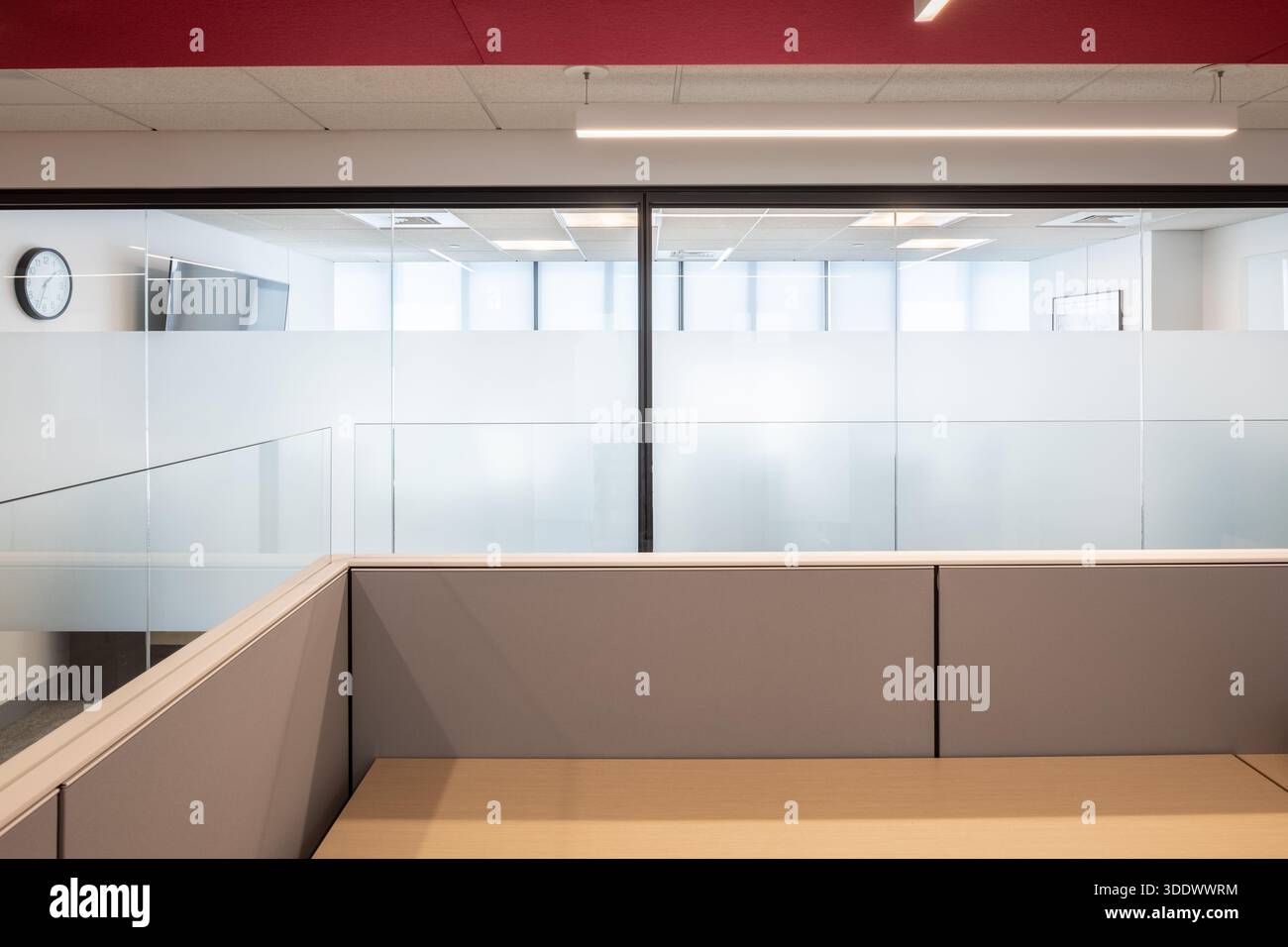 Eine minimalistische Wanduhr, die über einem Milchglasfenster in einem modernen, neu errichteten Bürogebäude montiert ist. Stockfoto