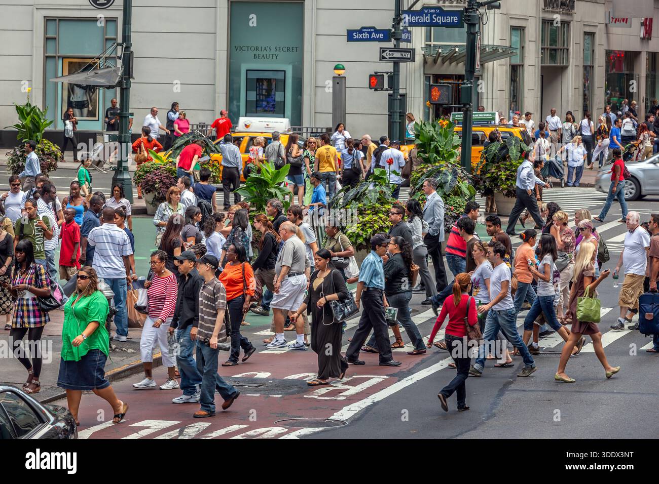 Die Menschenmassen bewegen sich durch die geschäftige Kreuzung von 6th Avenue und 34th Street in Midtown Manhattan, einem der aktivsten Fußgängerkorridore von New York City. Stockfoto