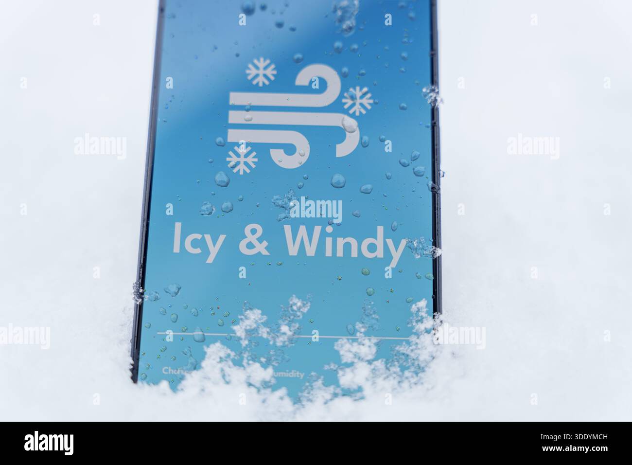 Smartphone steht im Schnee mit eiskalter und windiger Wettervorhersage auf dem Bildschirm, Wintersturmkonzept. Hochwertige Fotos Stockfoto