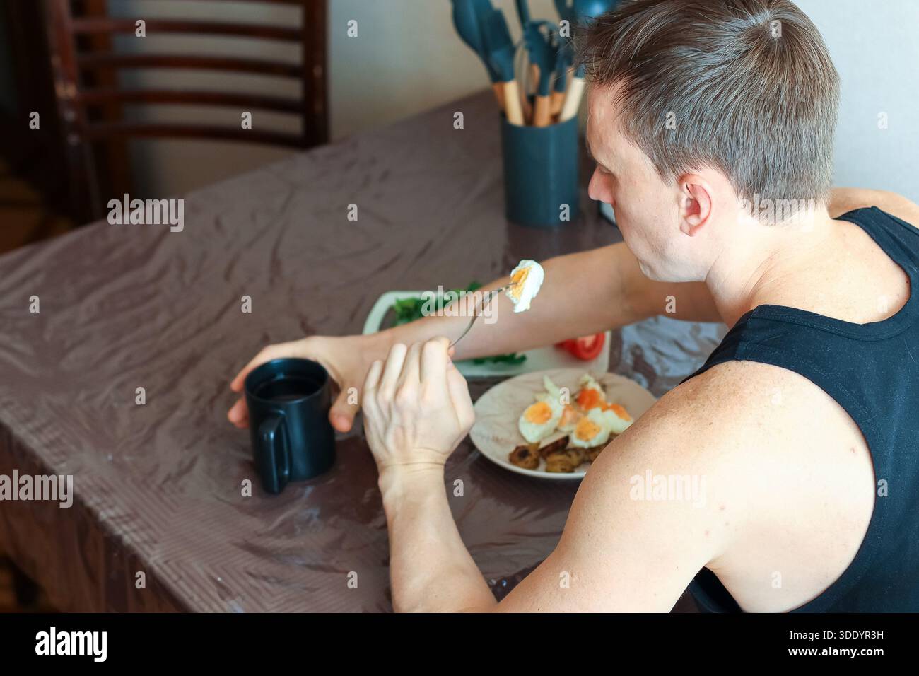 Erwachsene männliche Gabeln gekochtes Eierstück zwischen Gemüse und Ergänzungen auf dem Tisch Stockfoto