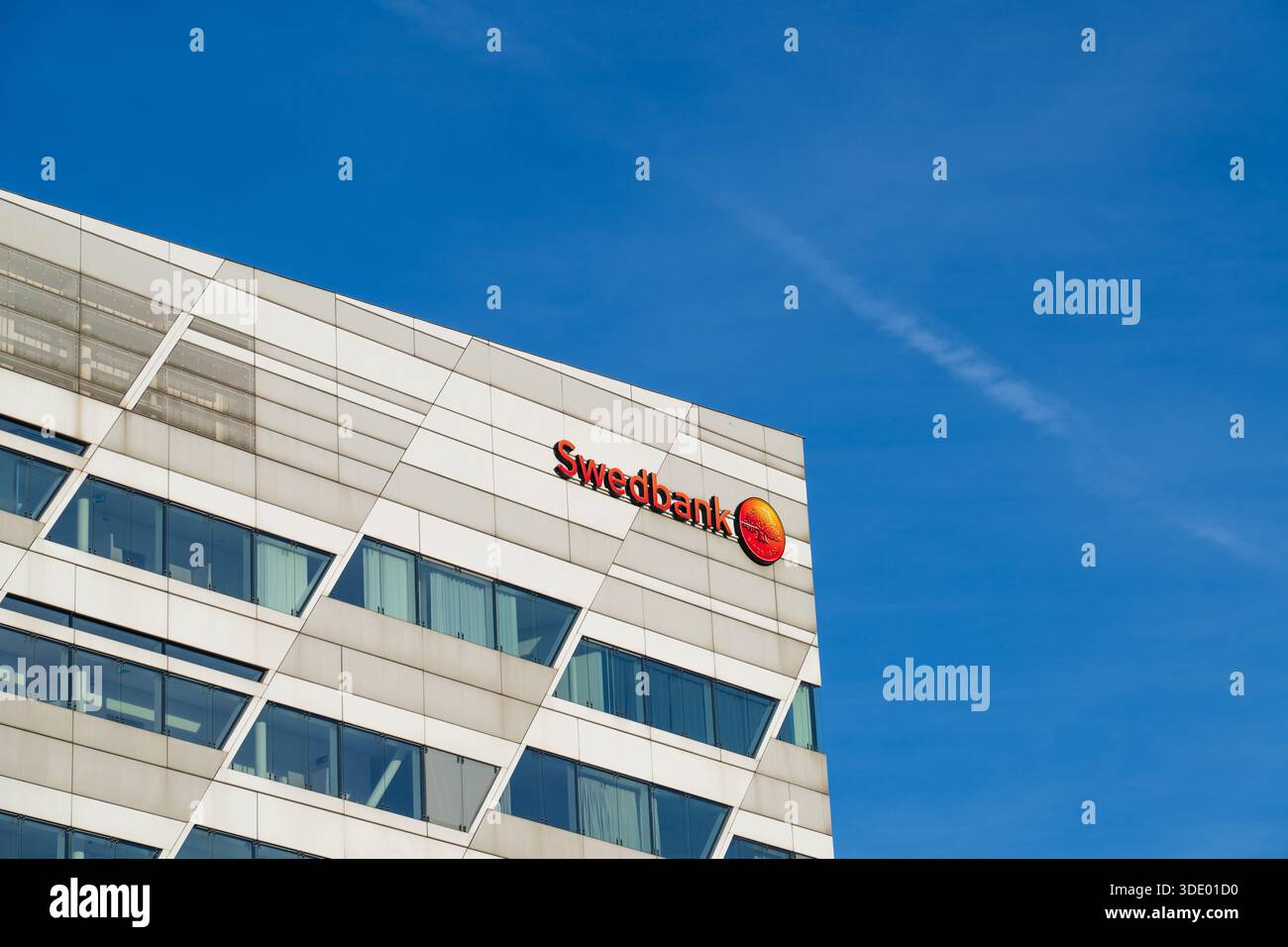 Die moderne Glasfassade des Swedbank-Hauptgebäudes mit ihrem Firmenlogo vor einem hellblauen Himmel in Sundbyberg, Stockholm, Schweden. Stockfoto