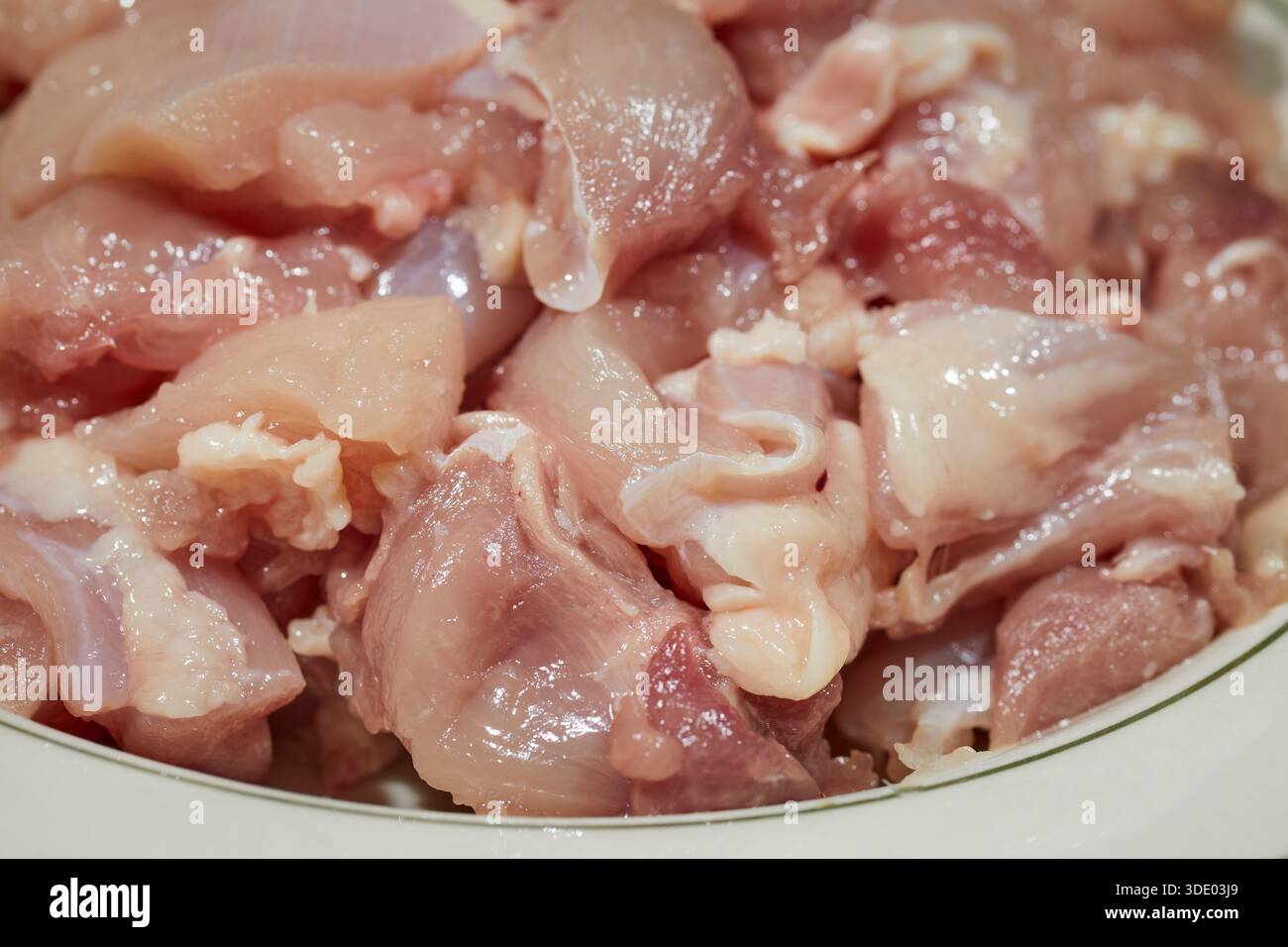 Gehackte Stücke von rohen, knochenlosen Hühnerschenkeln Stockfoto