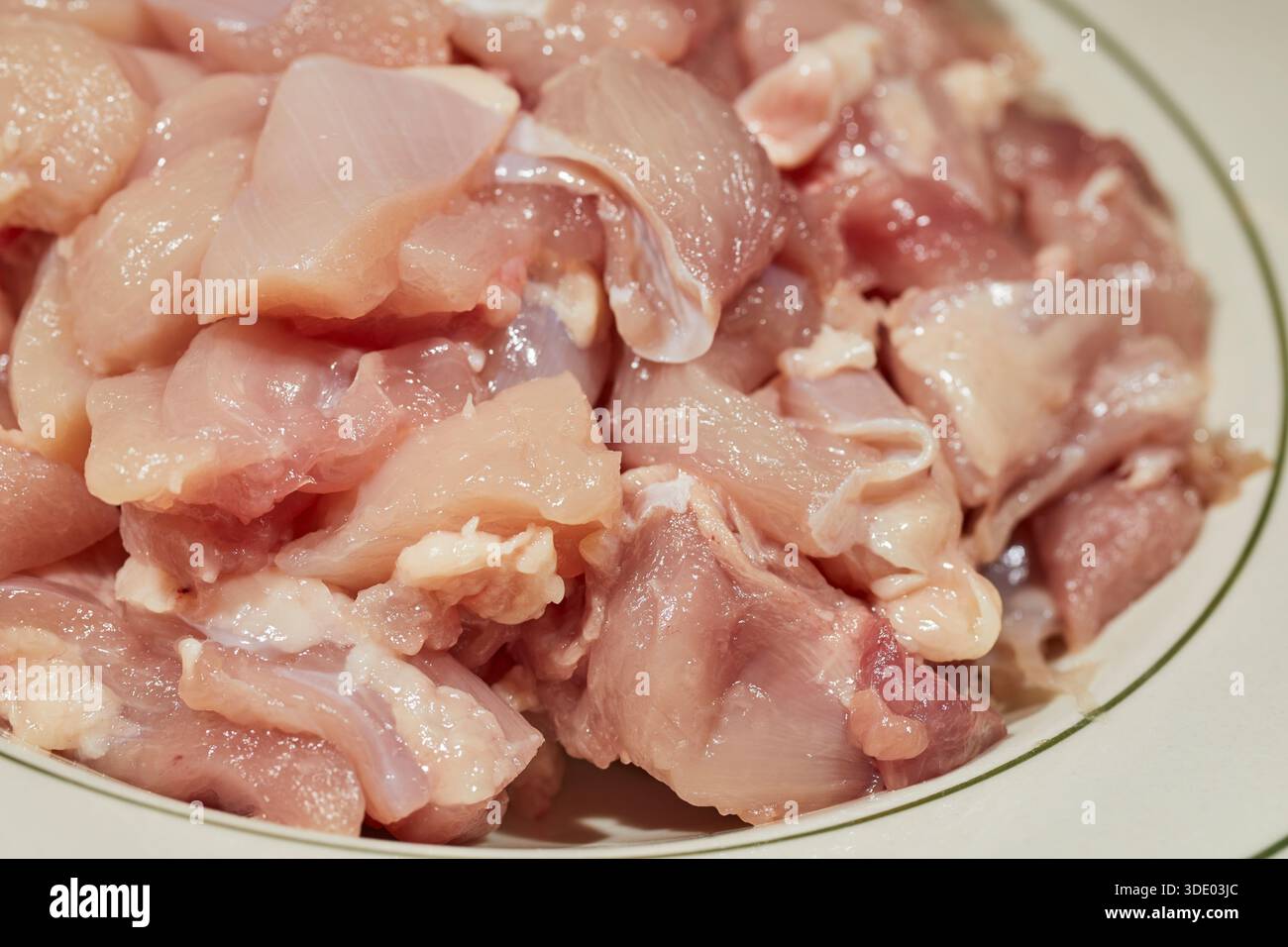 Gehackte Stücke von rohen, knochenlosen Hühnerschenkeln Stockfoto
