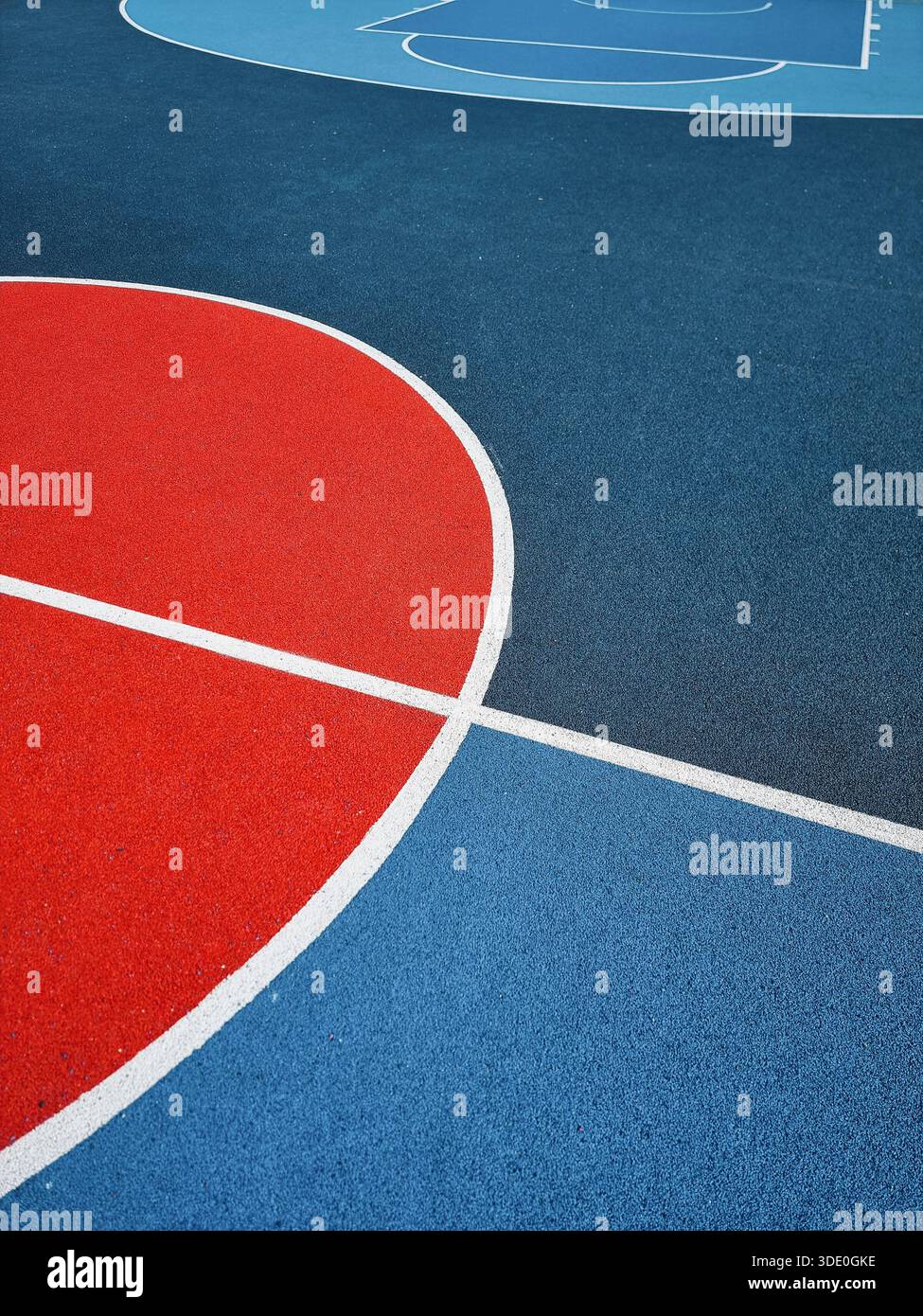 Rote und blaue Oberfläche des Basketballplatzes im Freien. Gummierter, strukturierter Sportboden mit weißen Linienmarkierungen und minimalistischer geometrischer Anordnung. Stockfoto