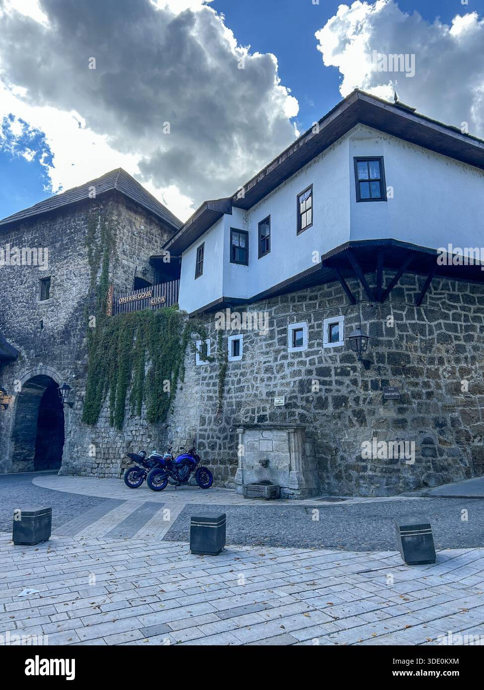 Blick auf historische Steinmauern und traditionelle Häuser in der Altstadt von Jajce, Bosnien und Herzegowina, gefangen unter dramatischen Wolken. - Smartphone-aufgenommenes Stockfoto