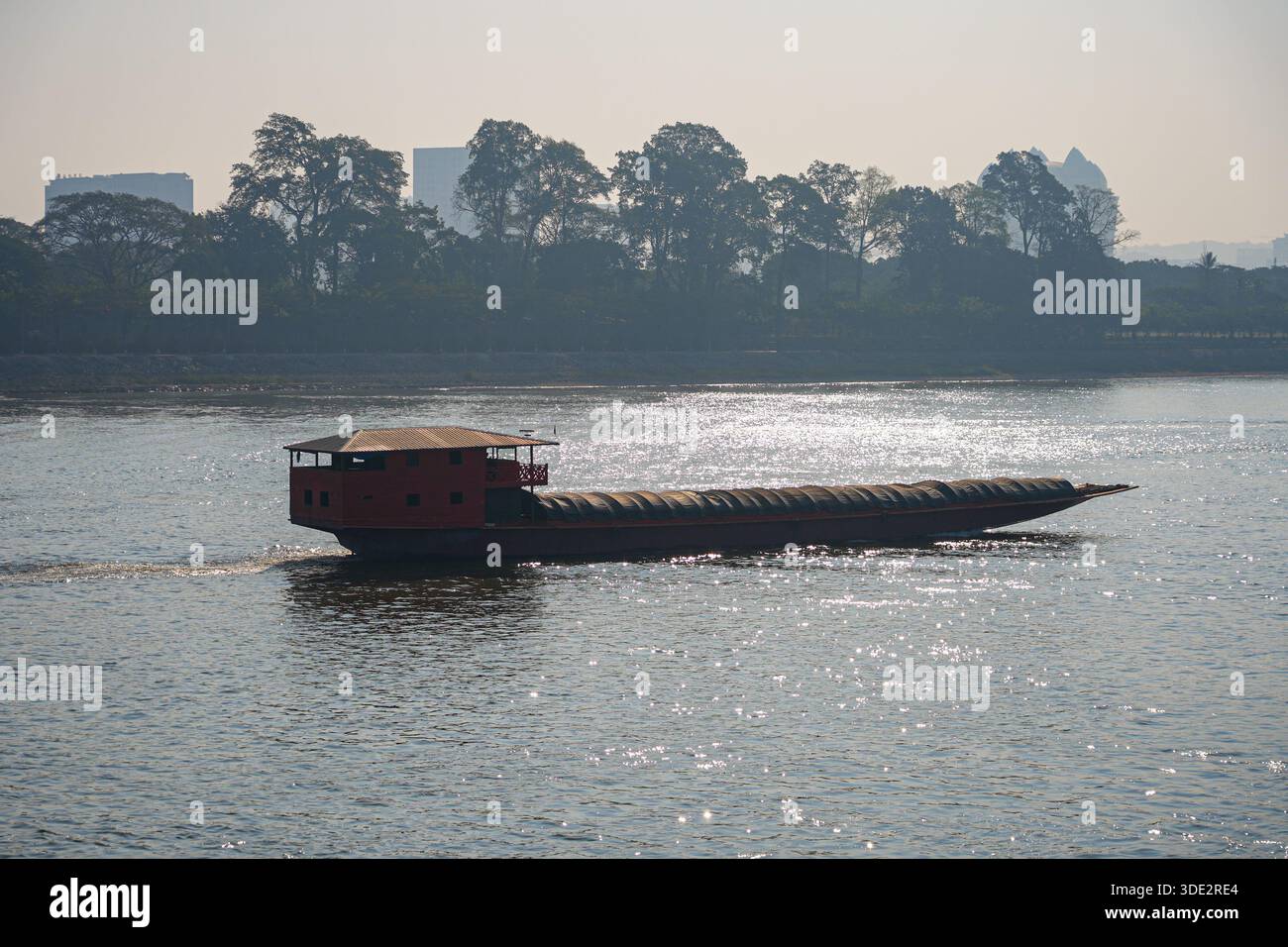 Ein Frachtschiff, das das glitzernde Wasser des Mekong im Goldenen Dreieck in Chiang Saen im Norden Thailands bei der dreifachen Grenzwette befährt Stockfoto