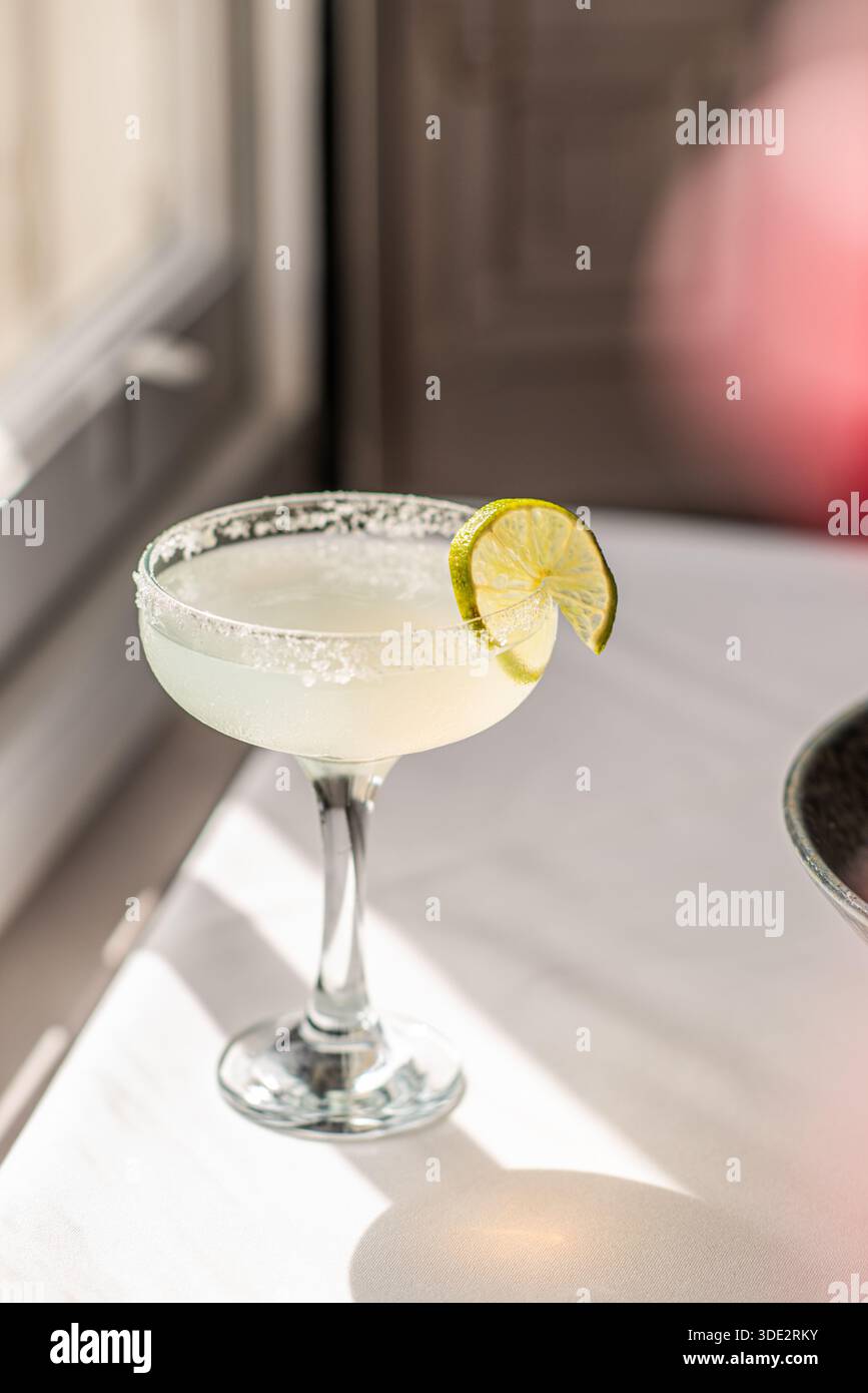 Klassischer Margarita-Cocktail in einem traditionellen Glas mit gesalzenem Rand und frischer Limettengarnitur. Erfrischendes alkoholisches Getränk. Stockfoto