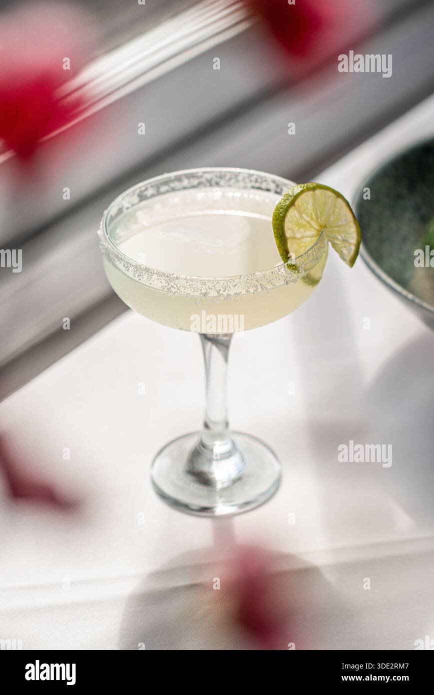 Klassischer Margarita-Cocktail in einem traditionellen Glas mit gesalzenem Rand und frischer Limettengarnitur. Erfrischendes alkoholisches Getränk. Stockfoto