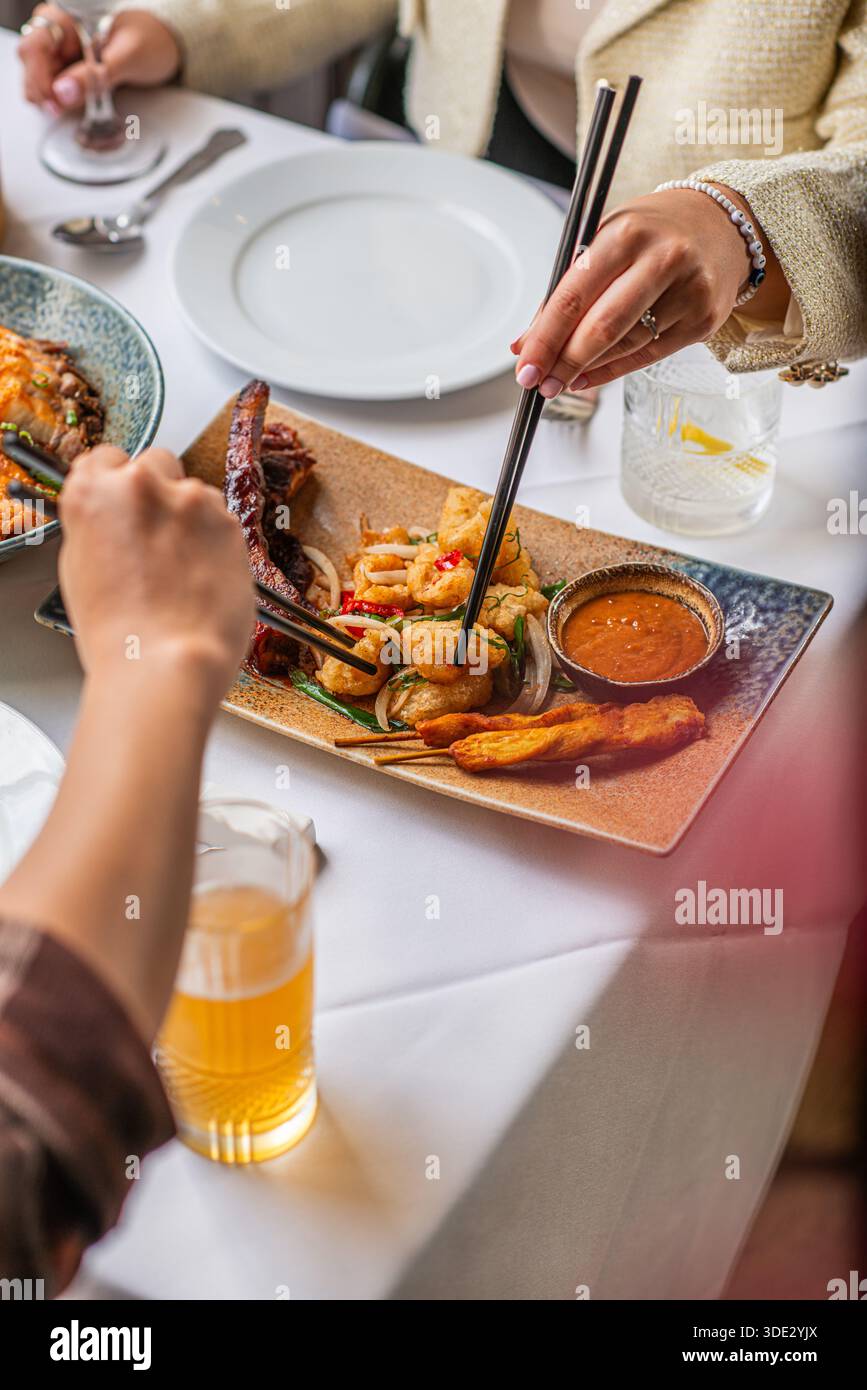 Gebratene Ente wird mit Essstäbchen in einem chinesischen Restaurant genossen, während zwei Personen das chinesische Neujahr mit einer gemeinsamen festlichen Mahlzeit feiern. Stockfoto
