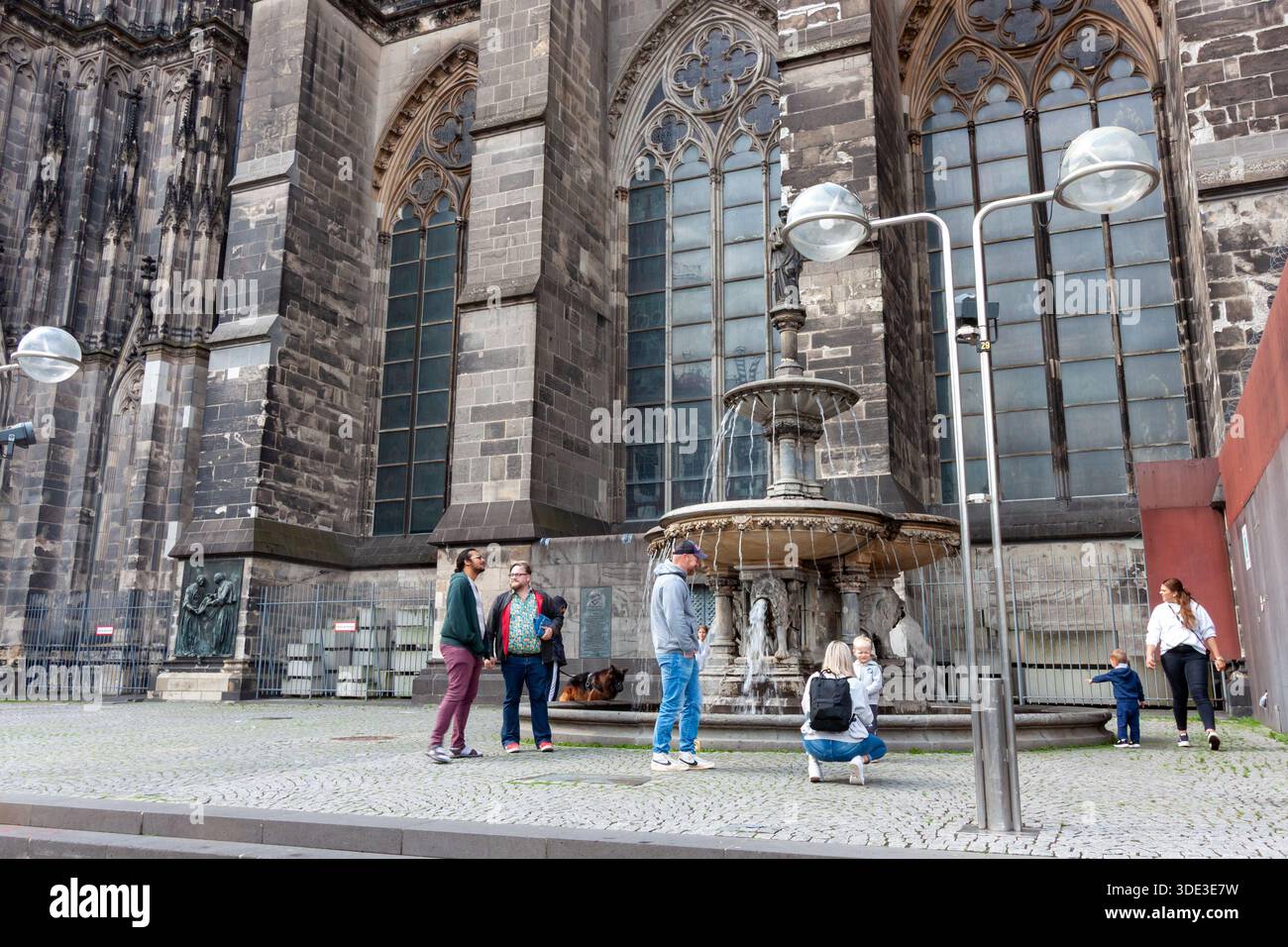 KÖLN, DEUTSCHLAND - 31. MAI 2024: Touristen am historischen Peter-Brunnen-Brunnen neben dem Kölner Dom. Gotische Steinarchitektur und m Stockfoto