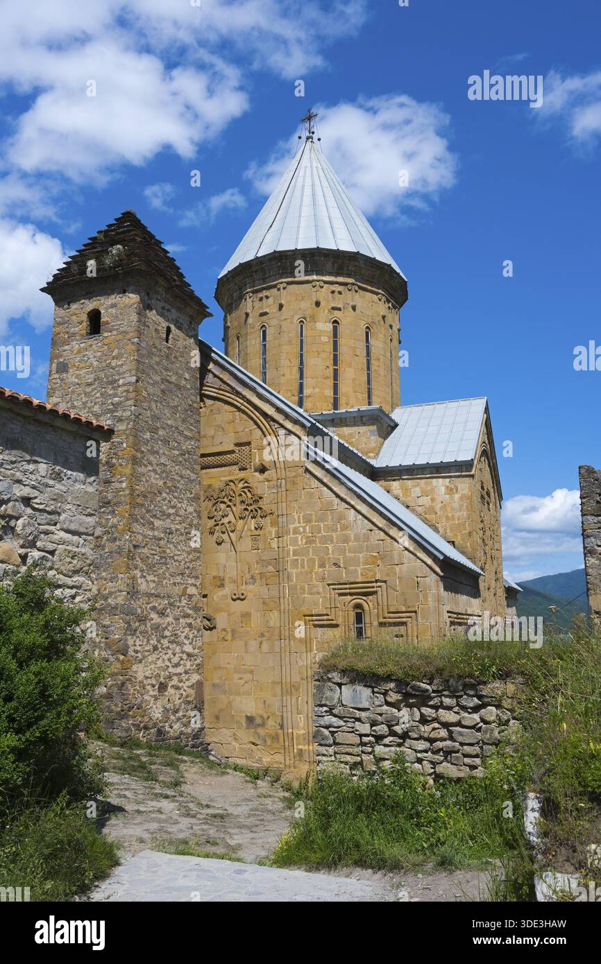 Mittelalterliche Steinkirche mit markantem Backsteinturm und üppiger Umgebung unter blauem Himmel, Schloss Ananuri, Stausee Zhinvali, Jinvali oder Shinvali, Stockfoto