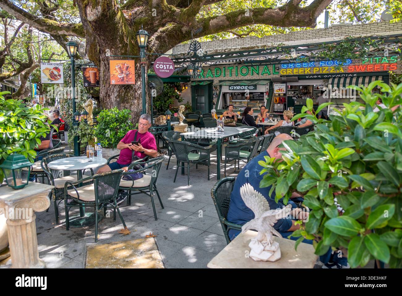 Touristen auf der Terrasse eines Cafés im Dorf Olympia, Griechenland Stockfoto