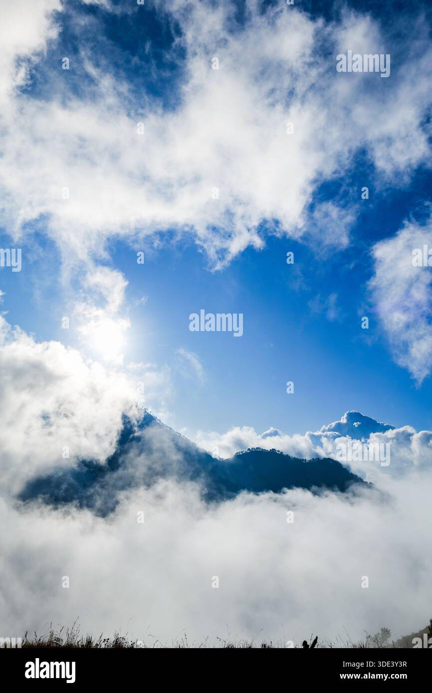 Berggipfel bedeckt von Wolkenmeer mit blauem Himmel am Morgen am Mount Rinjani, Lombok, Indonesien. Stimmungsvolles Bergnaturfoto für Abenteuer, Trekking, Bergsteigen Stockfoto
