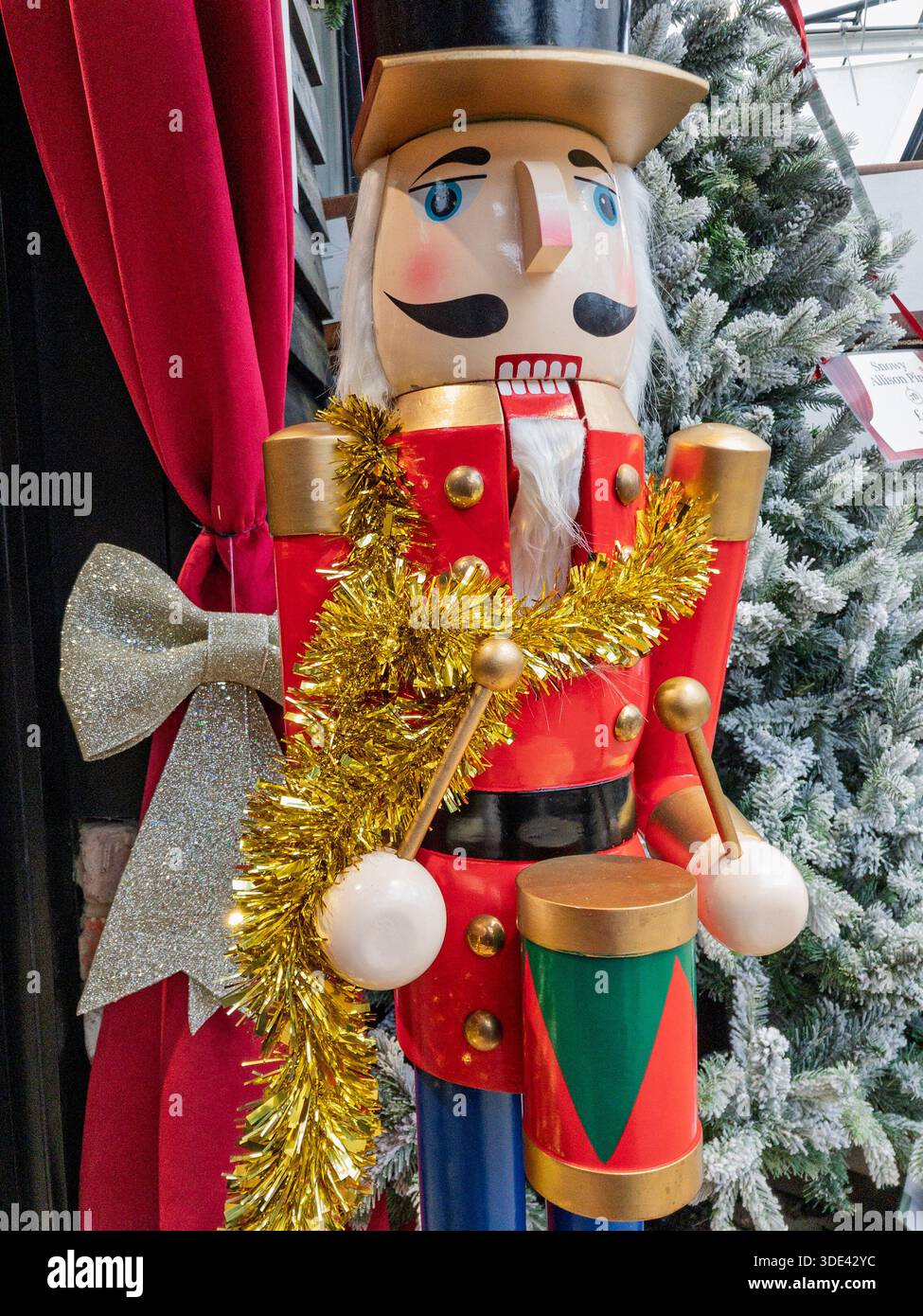Eine Nussknacker-Figur, mit Lametta überzogen, Teil einer Weihnachtsausstellung im britischen Gartencenter Stockfoto