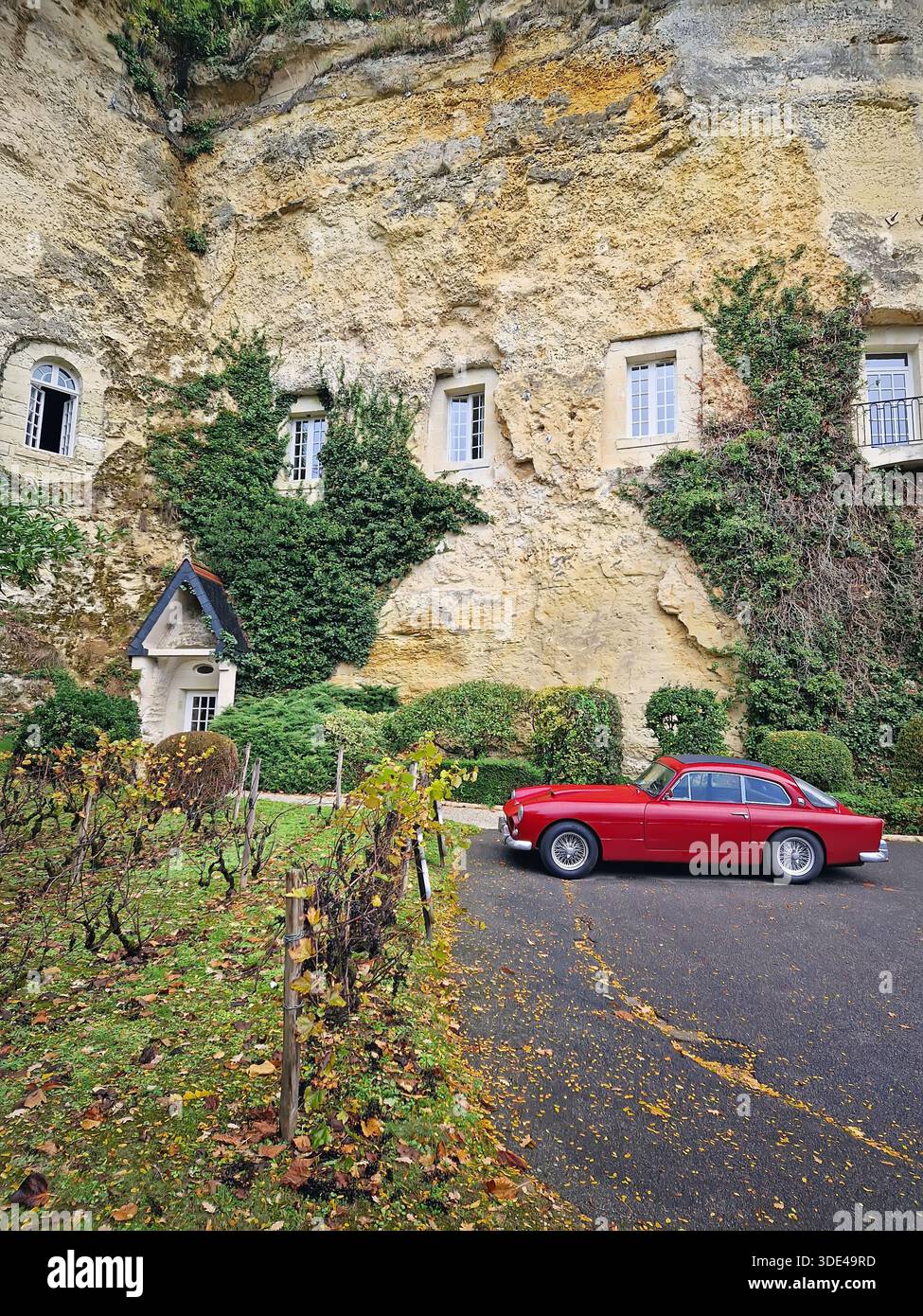Roocolorbon, Frankreich - 24. Oktober 2025: Ein roter Oldtimer, der in der Nähe der Kalkfelsen von Les Hautes Roches parkt. Wohnungen sind direkt geschnitzt Stockfoto