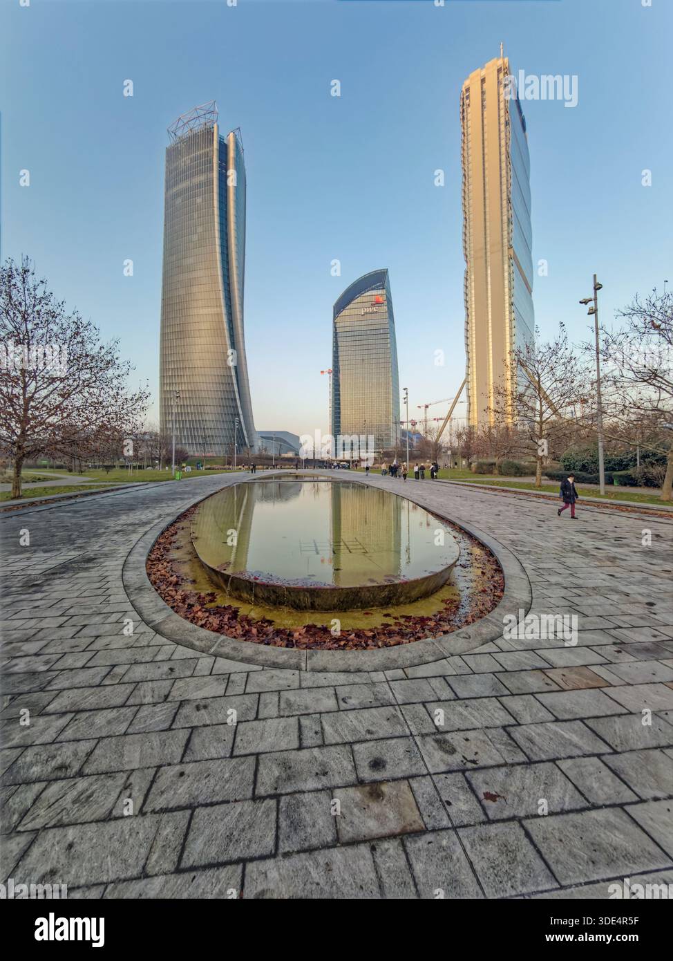 Mailand Italien. Stadtteil CityLife. Drei zeitgenössische Glastürme ragen über einem ruhigen Park mit einem flachen, ovalen Brunnen, der den Himmel und b reflektiert Stockfoto