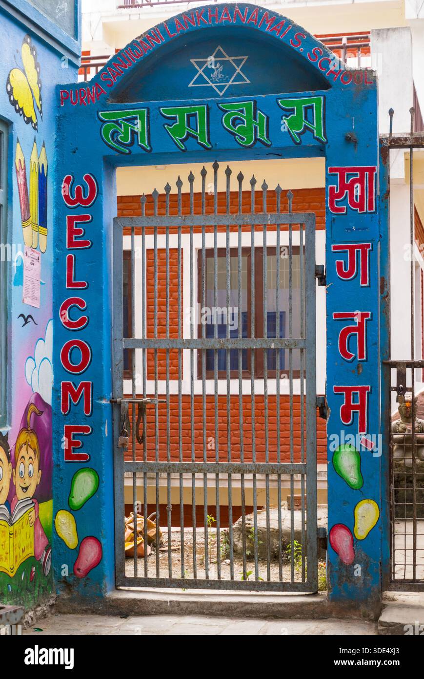 Ein dekoratives Schultor mit einem einladenden Schild und leuchtenden blauen und roten Elementen, die einen einladenden und verspielten Eingang für Kinder schaffen. Stockfoto