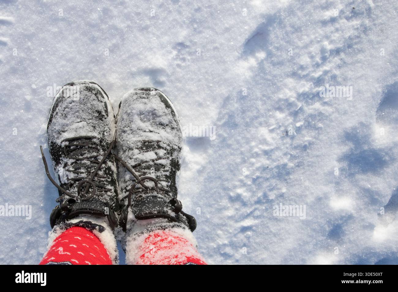 Person mit Winterstiefeln und gemusterten Leggings, die auf verschneiten Böden von oben steht Stockfoto