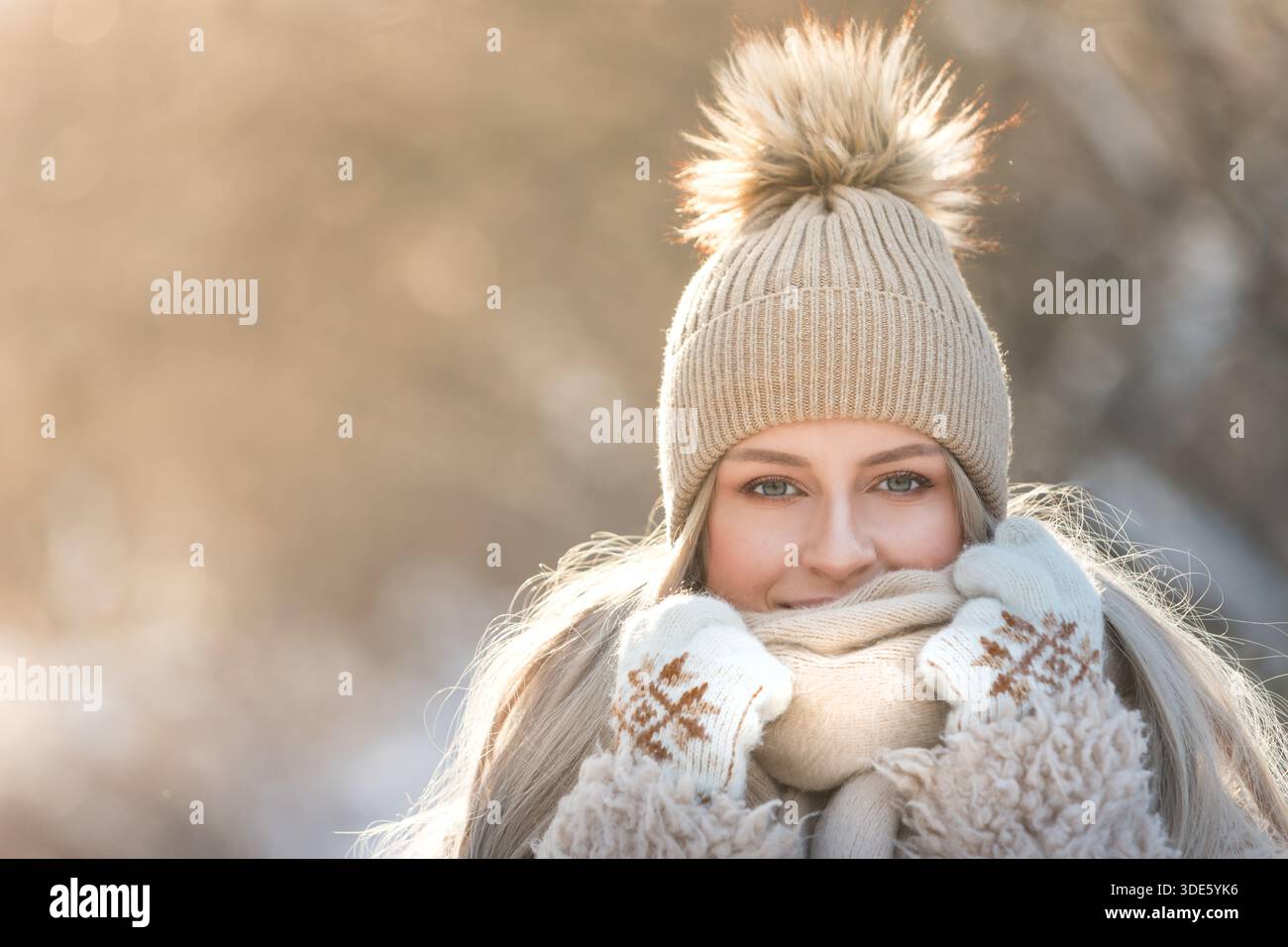 Porträt der jungen süßen Frau am sonnigen Wintertag. Eine Frau in warmen Kleidern lächelt und blickt in die Kamera Stockfoto