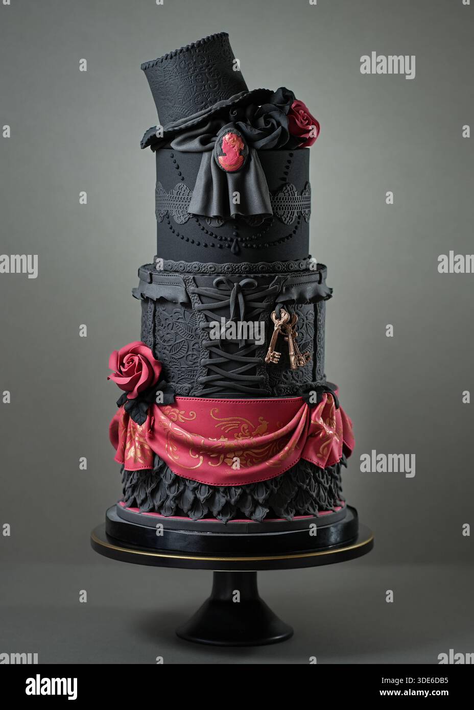 Elegante, mehrschichtige schwarze Hochzeitstorte im Burlesque- und viktorianischen Stil, mit Spitzendetails, Korsettendesign, Rosen, Cameo, und Stockfoto
