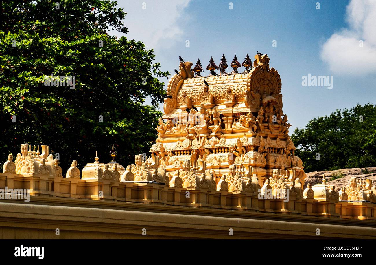 Kunstvoller goldener Tempelturm mit aufwändigen Schnitzereien vor einem blauen Himmel. Stockfoto