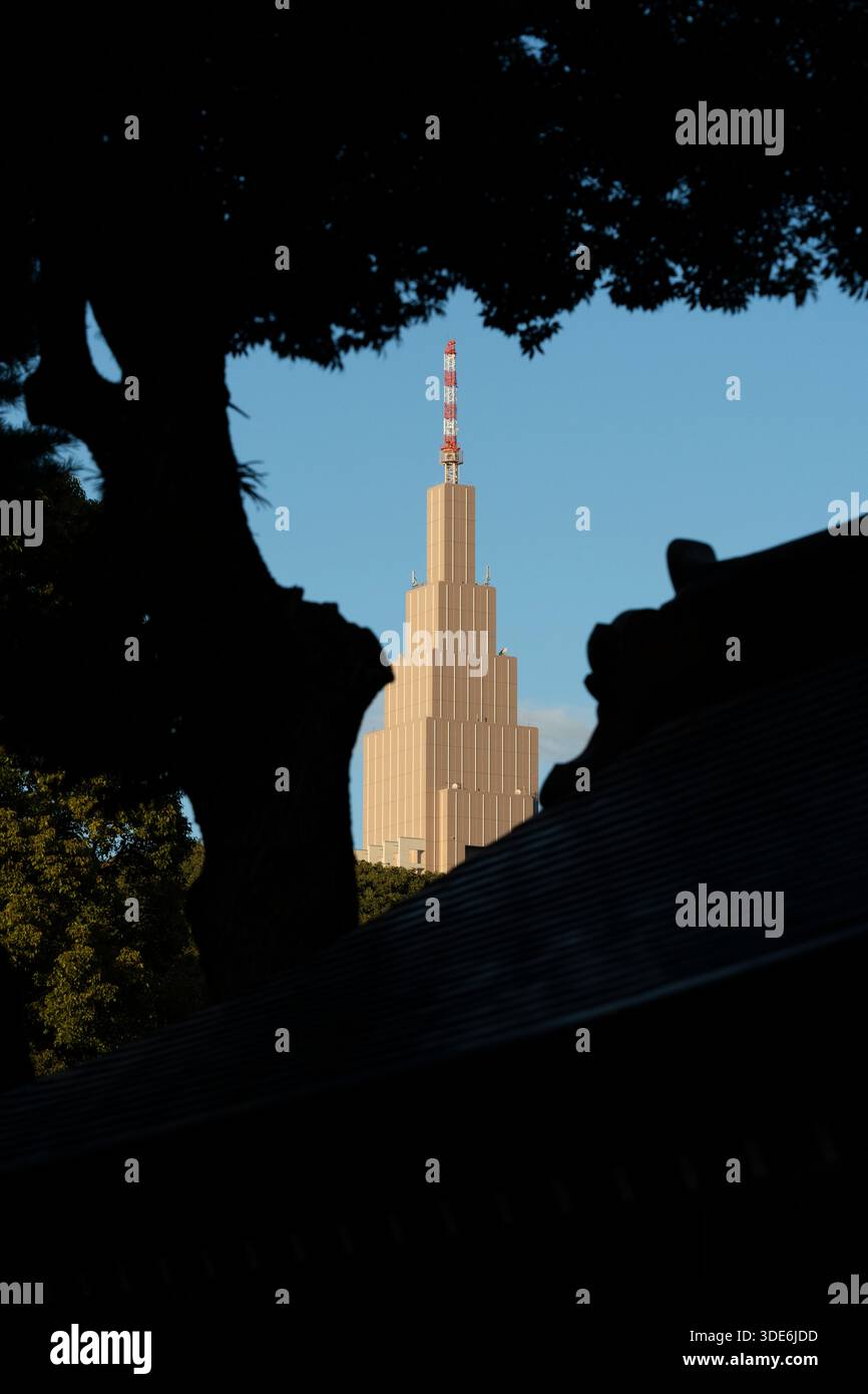 Der Tokyo Tower, eingerahmt von Bäumen und Tempeldächern, steht hoch vor dem blauen Himmel. Stockfoto