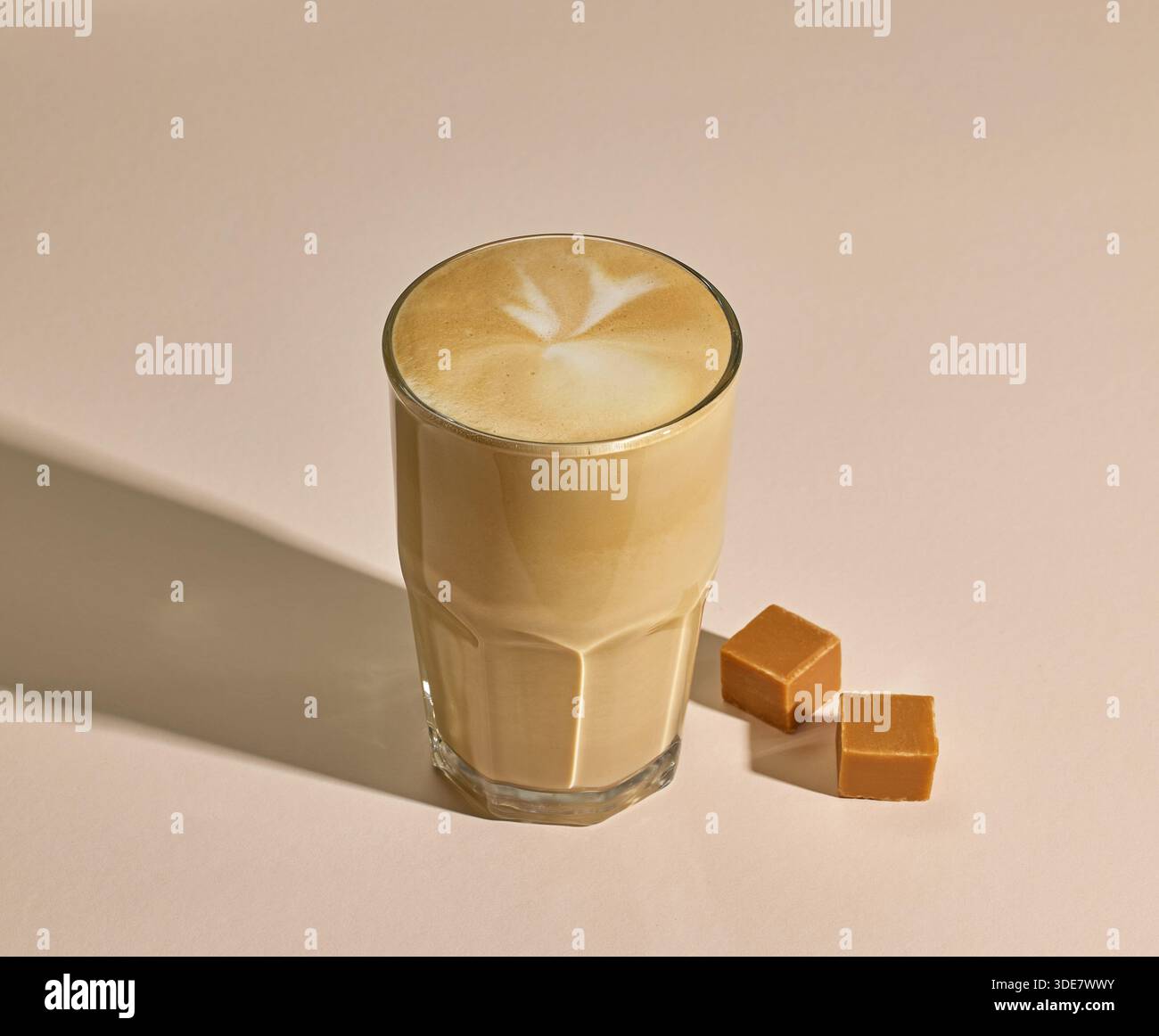 Glas Karamell Latte Kaffee auf beigefarbenem Hintergrund Stockfoto