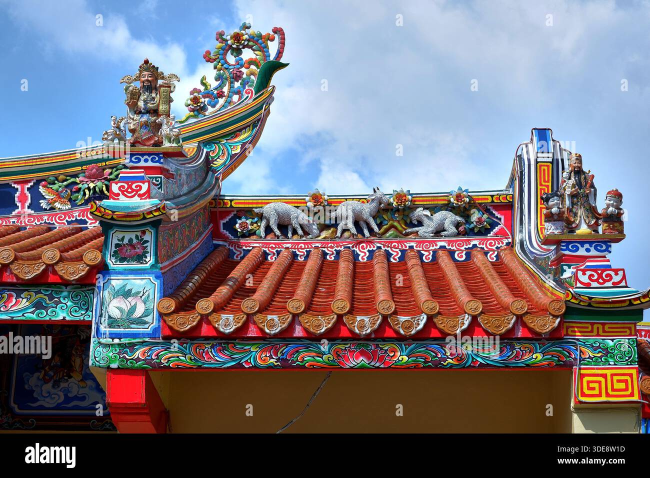 Ein hell bemaltes chinesisches Tempeldach auf dem Teochew-Friedhof zeigt eine Drachenbootsszene und Wächter vor blauem Himmel. Bangkok, Thailand. Stockfoto
