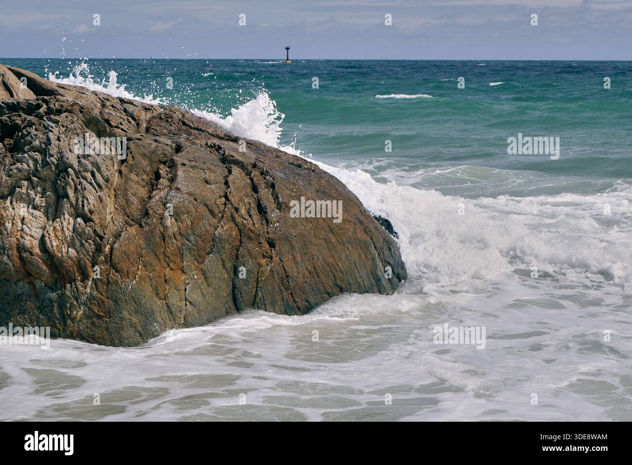 Ein riesiger Küstenfelsen steht in der Brandung, während Wellen gegen ihn brechen und Wellen am Ufer der Insel Koh Samet bilden. Stockfoto