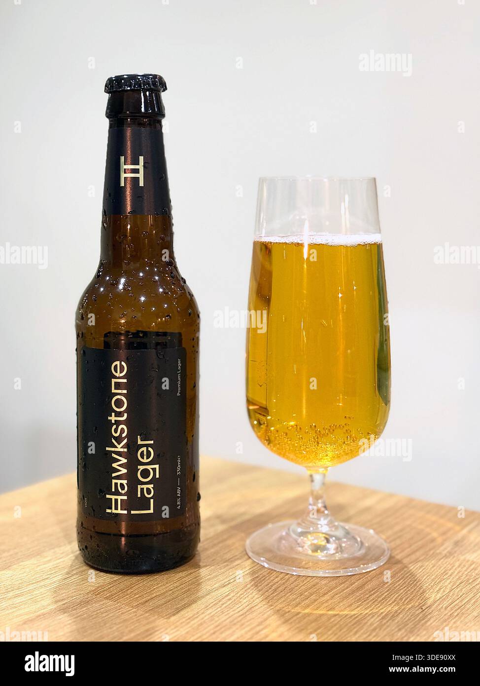 Goldenes Bier in einem Glas und eine Flasche Hawkstone Lager auf einer Küchenarbeitsfläche - Smartphone-aufgenommenes Stockfoto