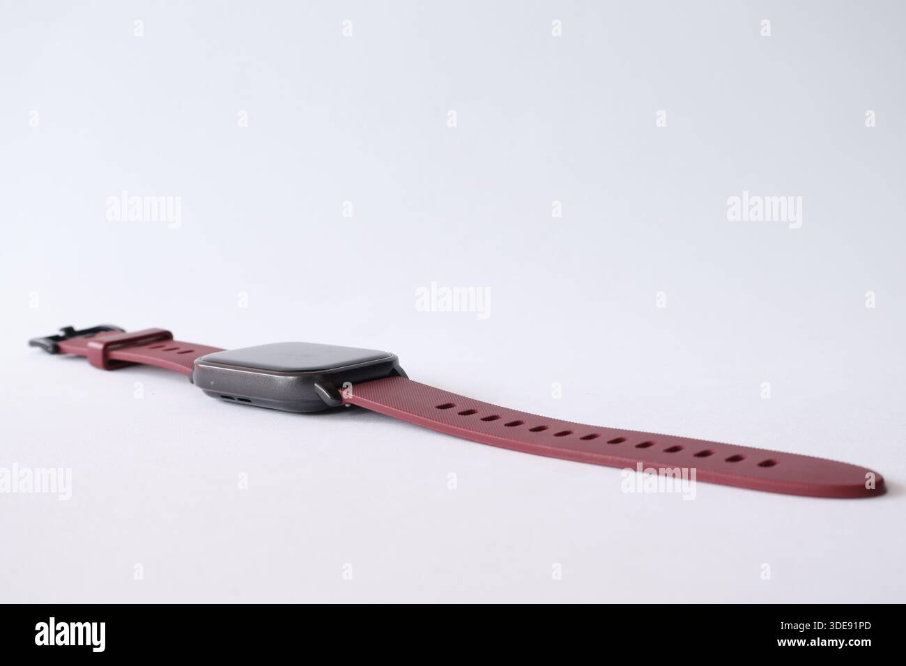 Seitenprofil einer modernen digitalen Smartwatch mit kastanienbraunem Silikonband auf weißem Hintergrund. Stockfoto