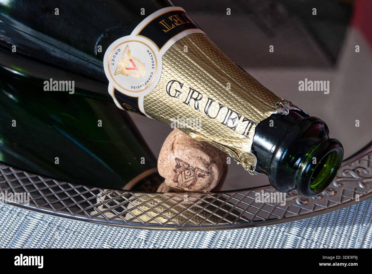 Nahaufnahme einer leeren Gruet Sektflasche und Kork auf einem Silbertablett, 2025, USA Stockfoto