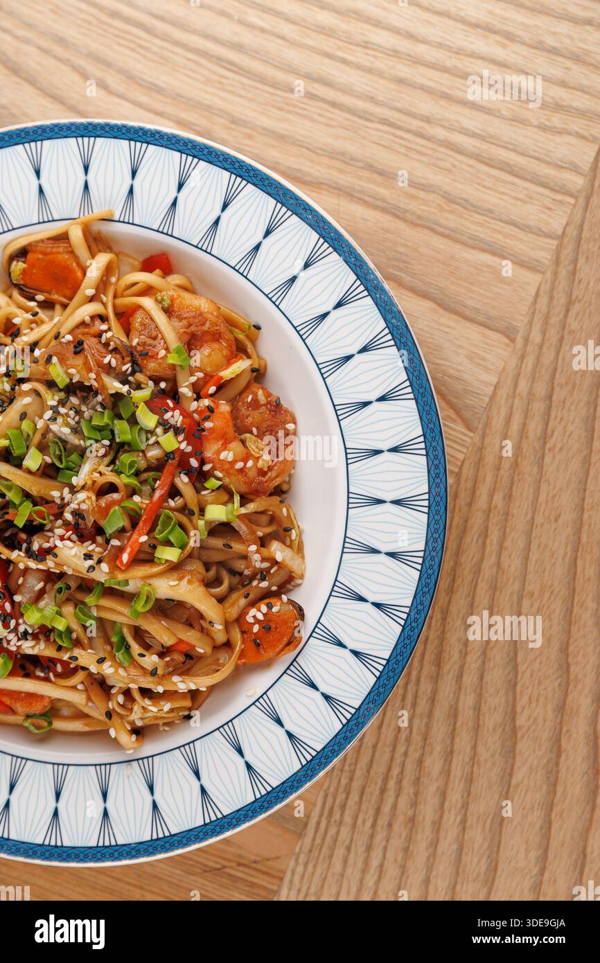 Auf einem Holztisch wird eine Sammlung von Gerichten aus verschiedenen Küchen ausgestellt. Jedes Gericht bietet einzigartige Zutaten und Kochstile, die Cu hervorheben Stockfoto