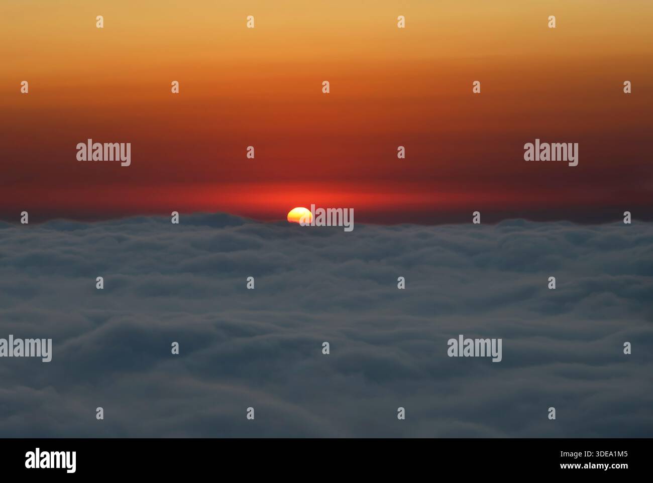 Sonnenuntergang hinter weichen Wolken auf Augenhöhe, wodurch eine ruhige und atmosphärische Himmelsszene entsteht. Stockfoto