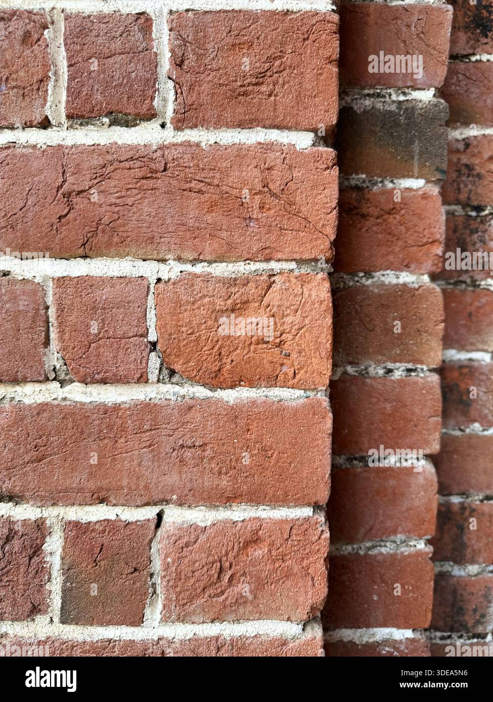 Nahaufnahme einer roten Ziegelwand mit sichtbaren Mörtellinien und strukturierter Oberfläche - Smartphone-aufgenommenes Stockfoto