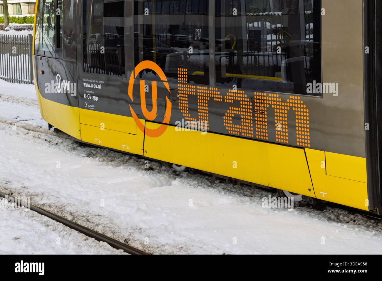 Nahaufnahme des orangefarbenen und grauen U-Tram-Logos an der Seite eines gelben ÖPNV-Fahrzeugs in Utrecht an einem verschneiten Wintertag. Utrecht Neth Stockfoto