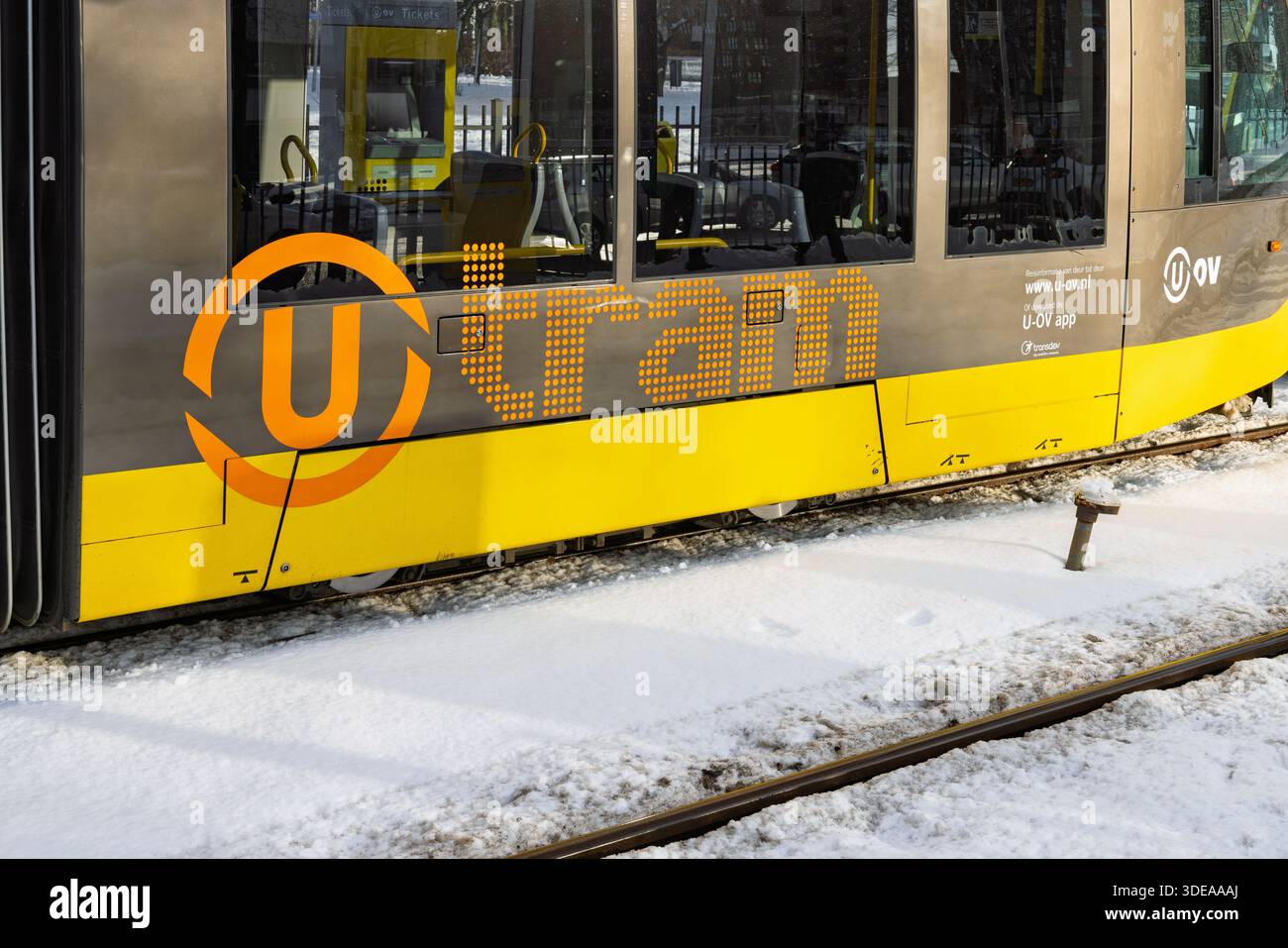Nahaufnahme des orangefarbenen und grauen U-Tram-Logos an der Seite eines gelben ÖPNV-Fahrzeugs in Utrecht an einem verschneiten Wintertag. Utrecht Neth Stockfoto